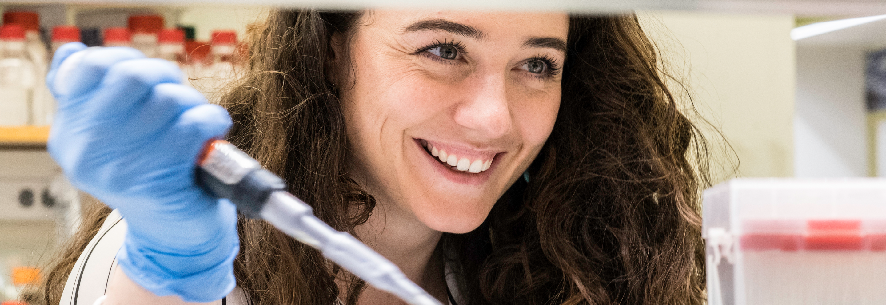 Scientist holding a pipette, seen through a lab bench