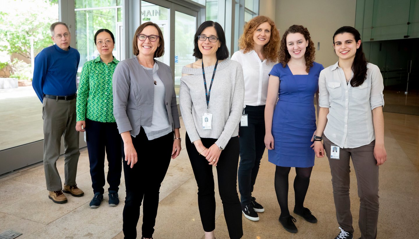 Group photo of scientists, standing in a light room