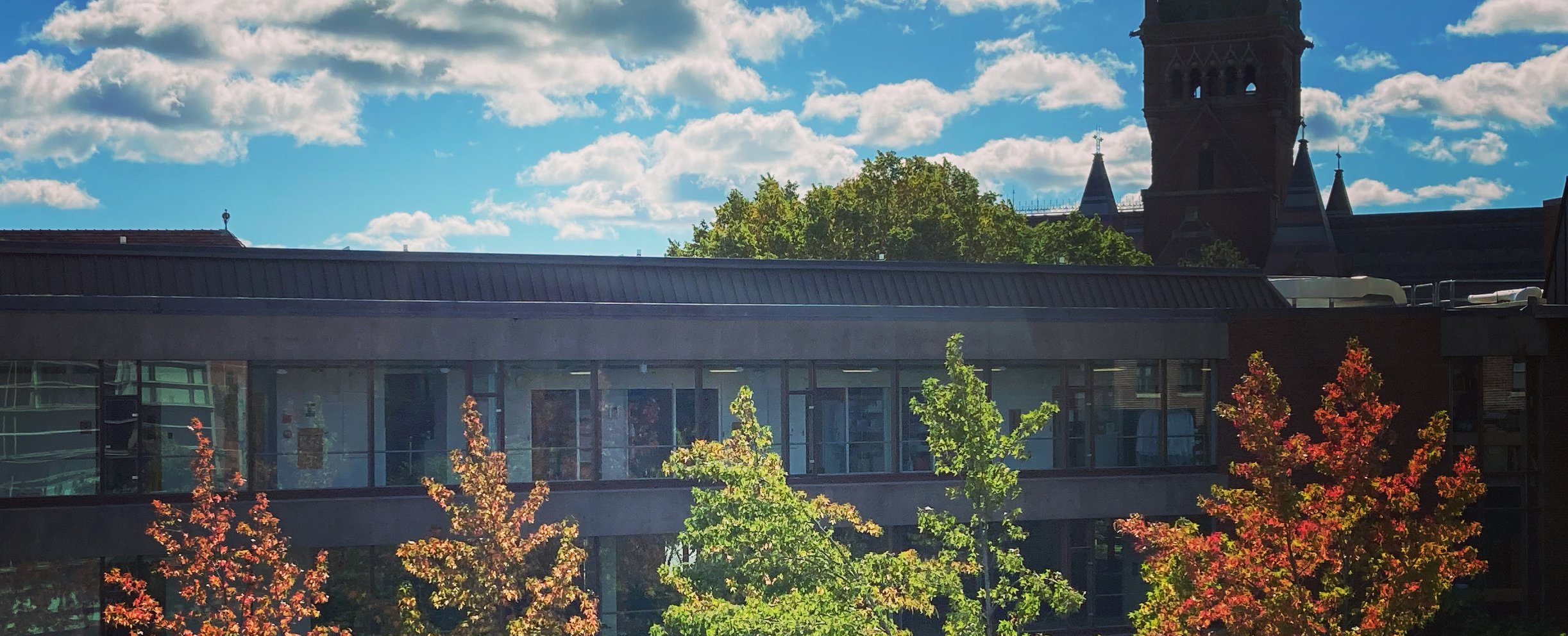 View of Sherman Fairchild lab with trees in the foreground and a partly cloudy sky in the background