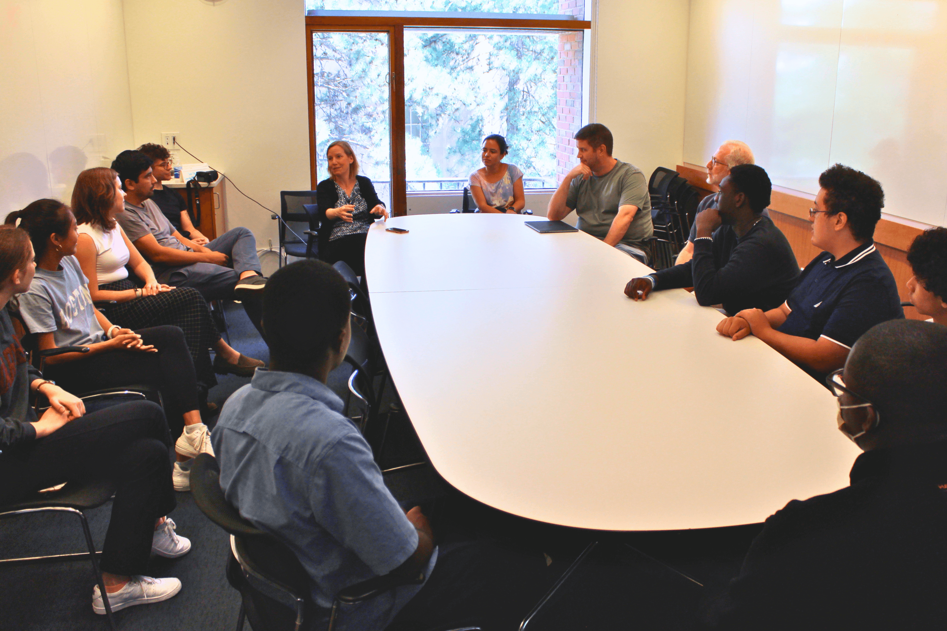 A group of students and faculty sit around a conference table 