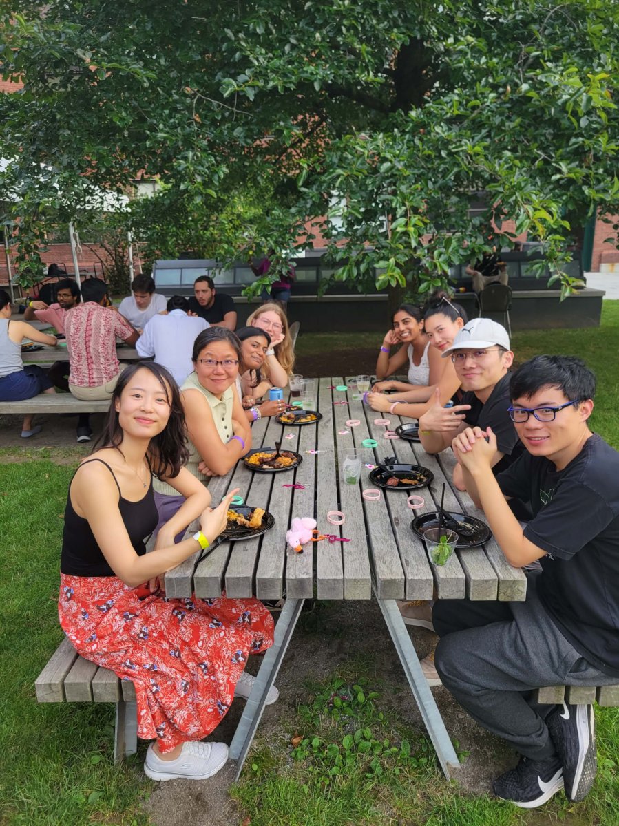 A group of people sitting outside at a picnic table