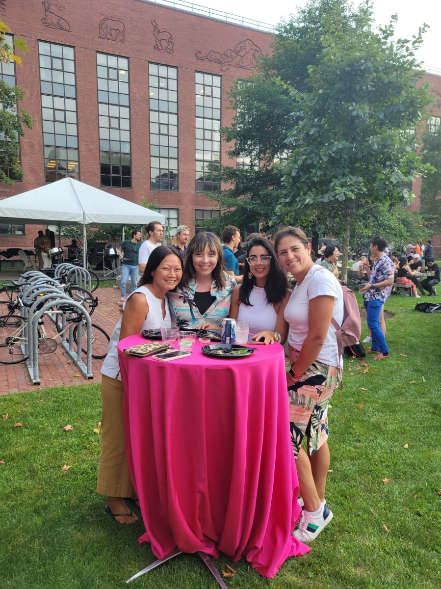 Four people standing at a pink table outside
