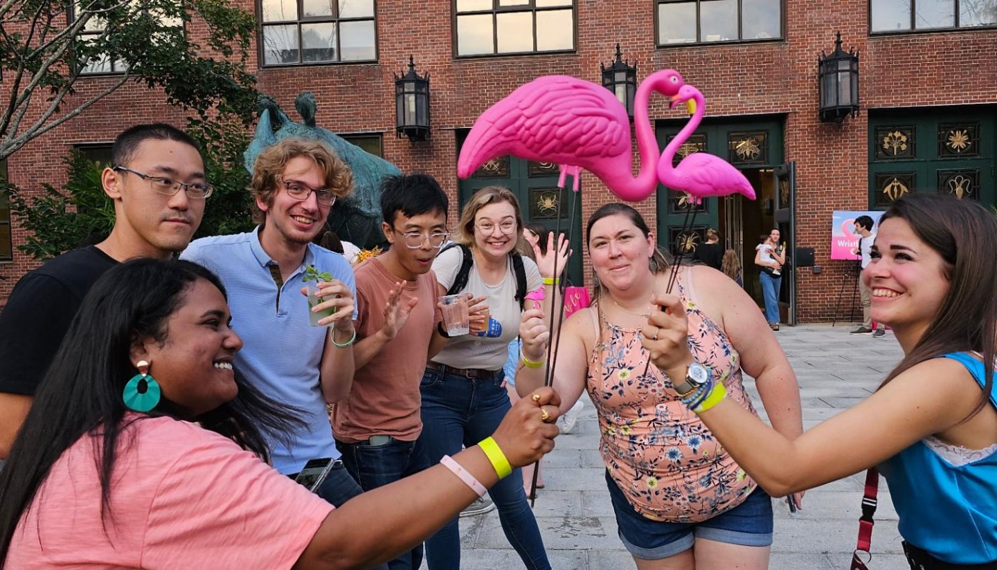 A group of people holding plastic flamingos