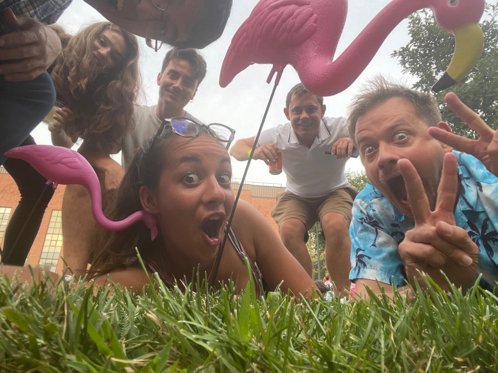 A group of people taking a selfie together outside with plastic flamingos