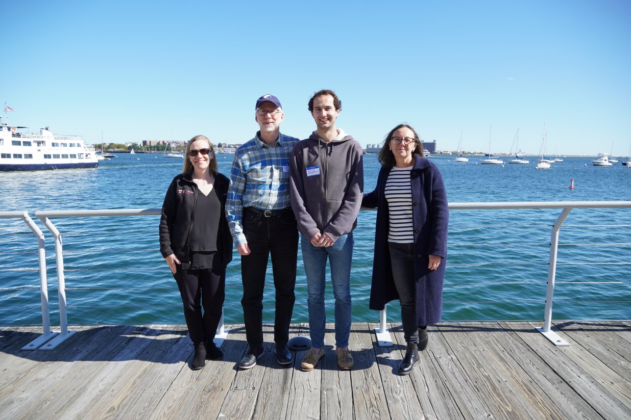Four people standing in front of an ocean view