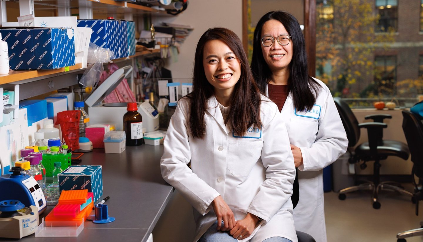 Two women in lab coats sitting in a research lab.
